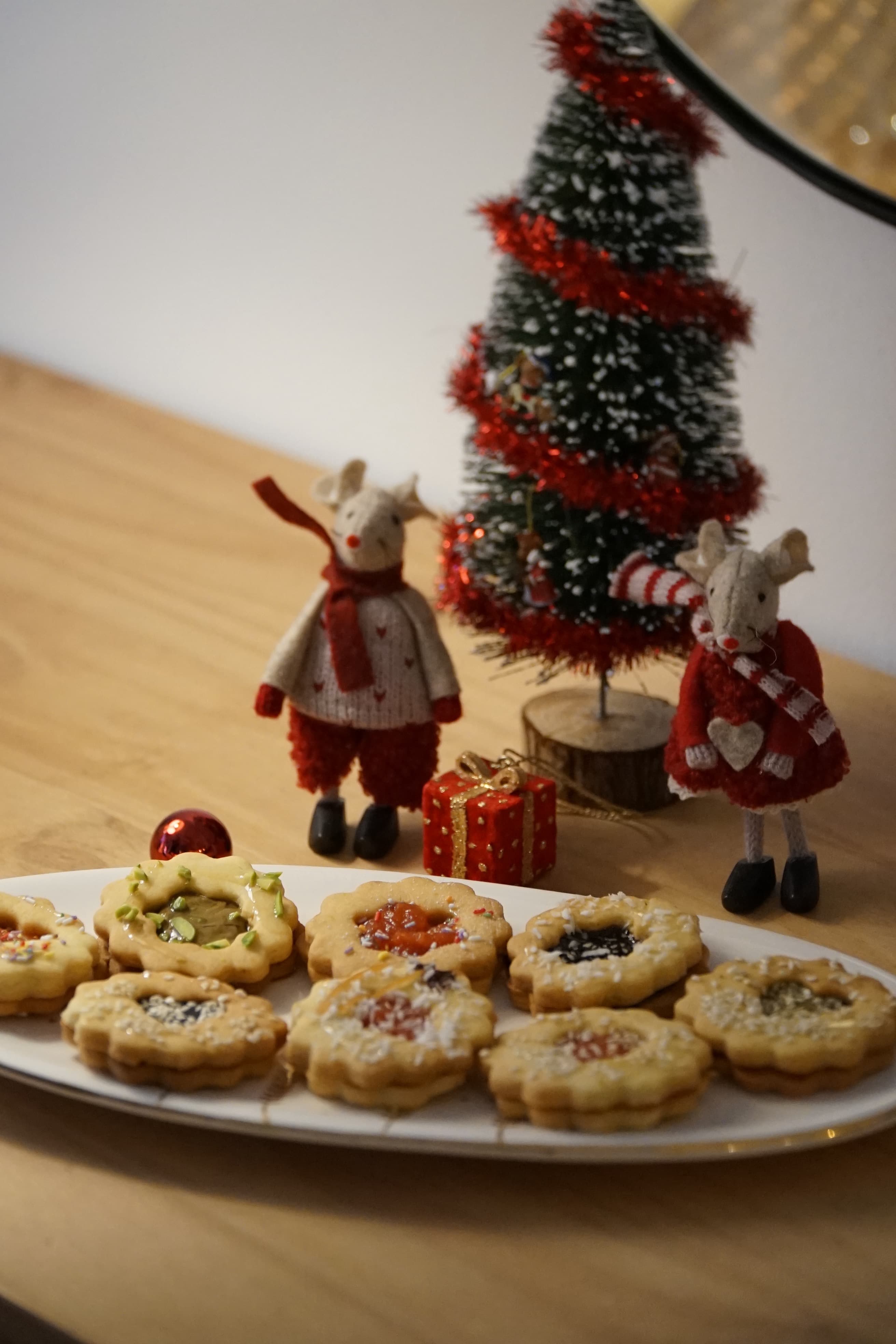 A baker sprinkling pistachios on a tray of baklava.